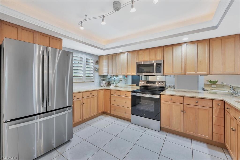 12945 Vanderbilt Drive, Unit 304 Naples, FL 34110 - Photo 6 of 45 a kitchen with granite countertop a refrigerator stove top oven and sink