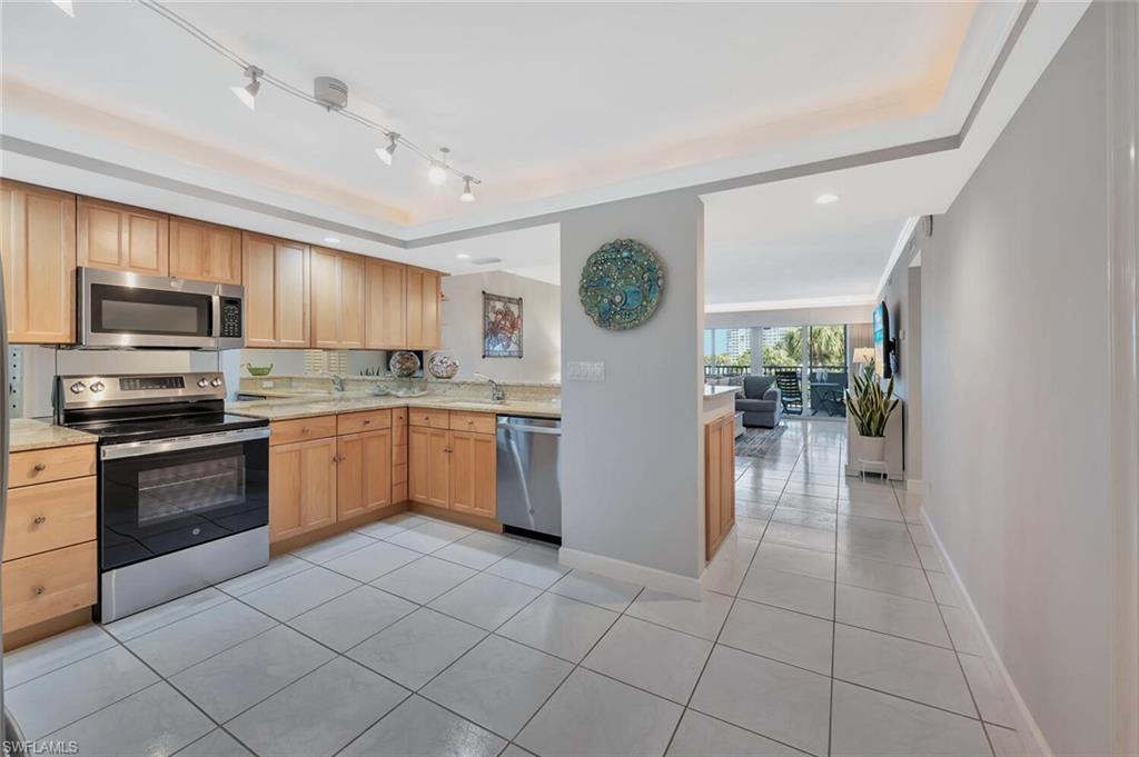 12945 Vanderbilt Drive, Unit 304 Naples, FL 34110 - Photo 7 of 45 a kitchen with granite countertop a refrigerator and a stove top oven