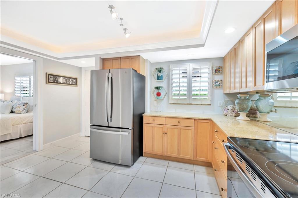 12945 Vanderbilt Drive, Unit 304 Naples, FL 34110 - Photo 10 of 45 a kitchen with stainless steel appliances granite countertop a refrigerator sink and cabinets