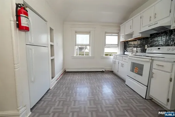 a kitchen with granite countertop a stove and white cabinets