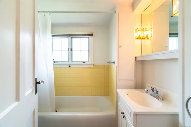 a bathroom with a bathtub sink and mirror