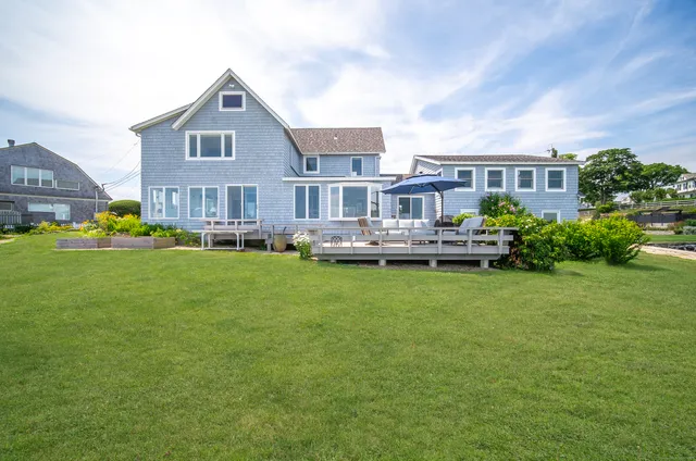 a front view of a house with garden and trees