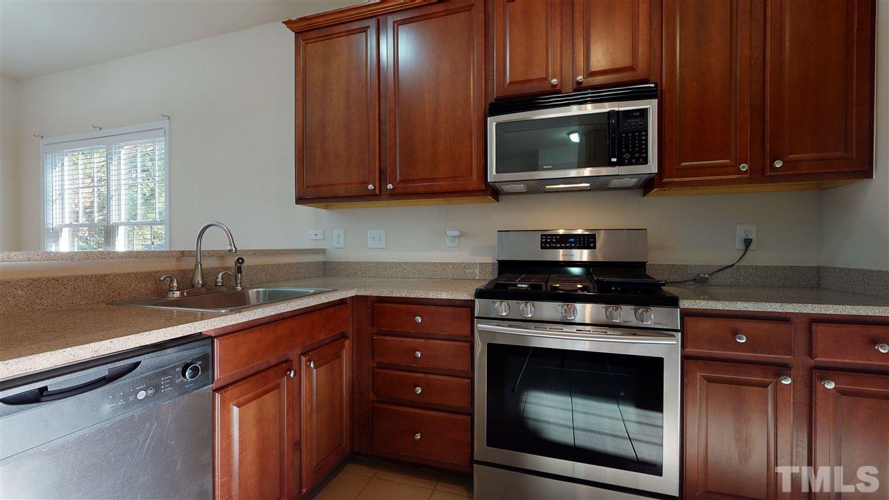 2105 Cook Road Durham, NC 27713 - Photo 28 of 29 a kitchen with granite countertop wood cabinets and stainless steel appliances
