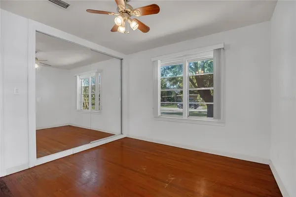 a view of an empty room with a window and wooden floor