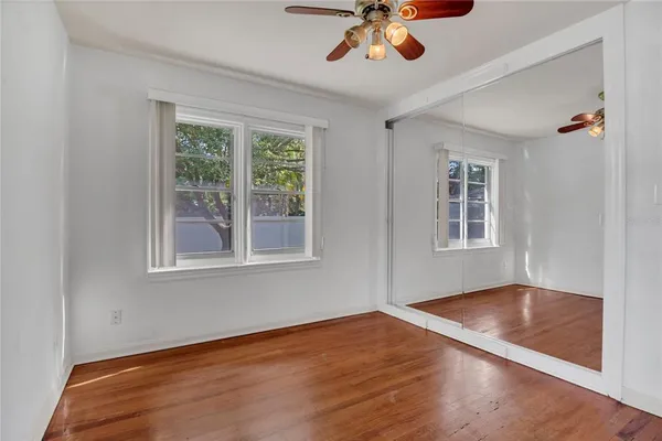 a view of empty room with wooden floor and fan