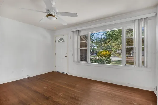 a view of empty room with wooden floor and fan