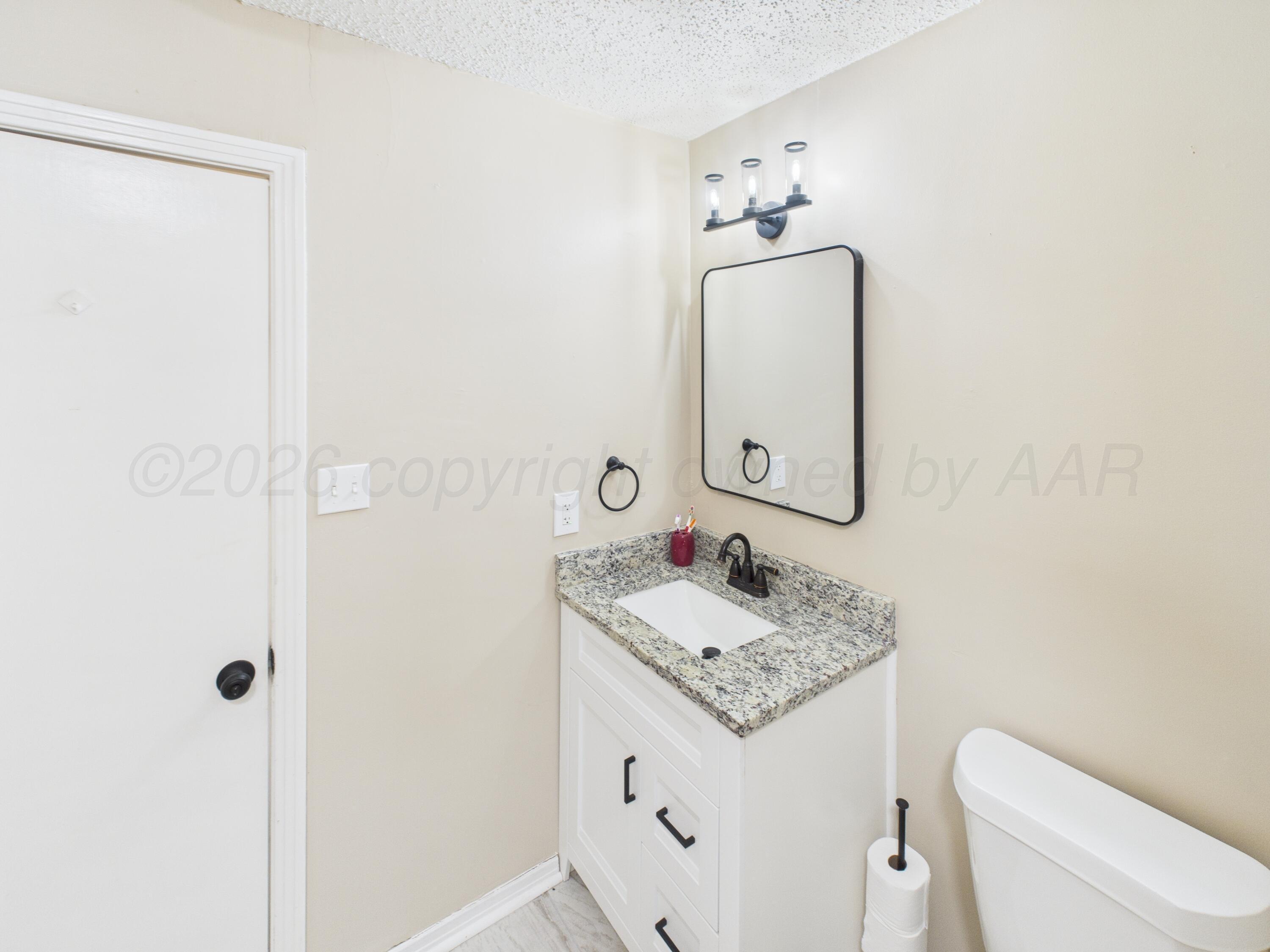 1816 Tularosa Street Amarillo, TX 79102 - Photo 18 of 24 a bathroom with a granite countertop sink a toilet and mirror