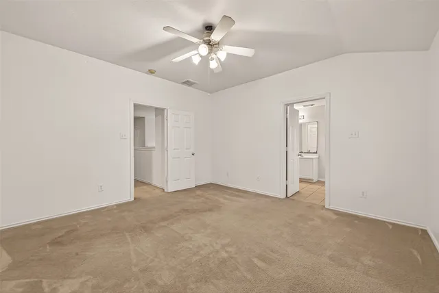 an empty room with fan and a chandelier fan