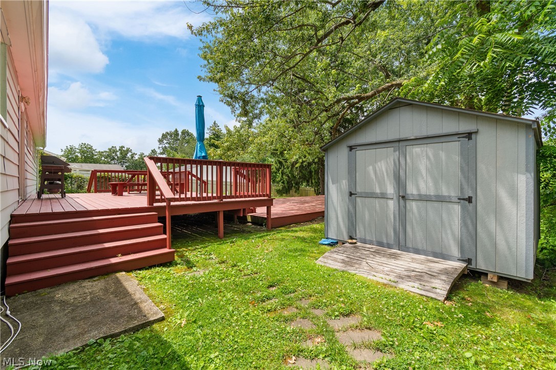 5768 Nolley Road Akron, OH 44319 - Photo 28 of 38 Spacious backyard featuring a multi-level wood deck with railings, a storage shed with double doors, and established green lawn areas