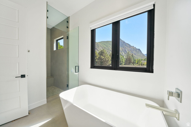 3667 Little Cottonwood Road, Unit 1 Sandy, UT 84092 - Photo 20 of 49 Freestanding soaking tub with a modern brushed nickel faucet and a large black-framed window showcasing mountain scenery