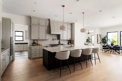 a large kitchen with kitchen island a dining table chairs and white cabinets