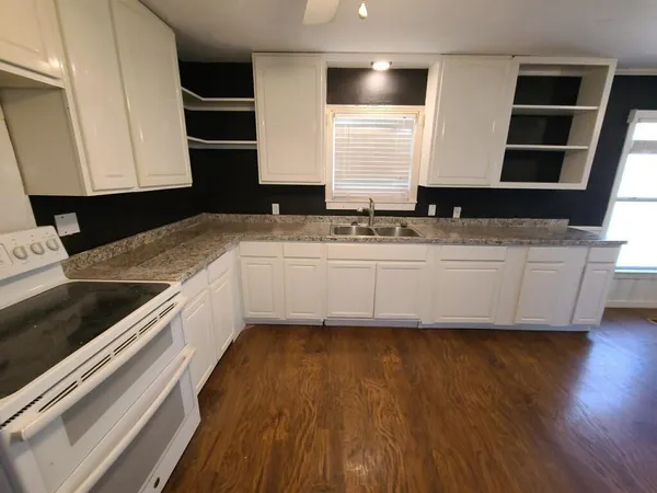 a kitchen with granite countertop white cabinets and white appliances