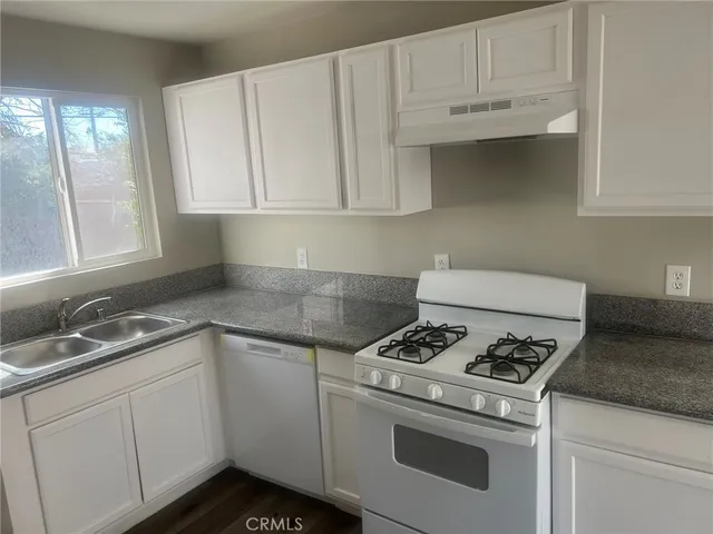 a kitchen with granite countertop white cabinets and white appliances
