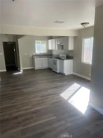 a view of kitchen and empty room with wooden floor and windows