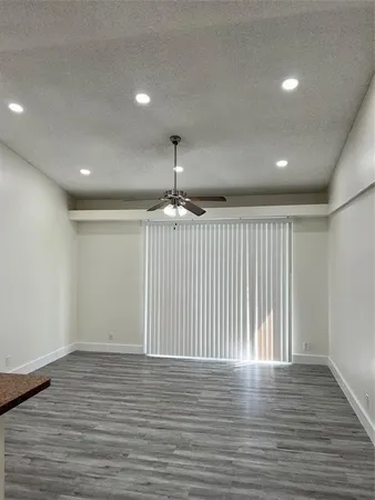 an empty room with wooden floor chandelier and windows