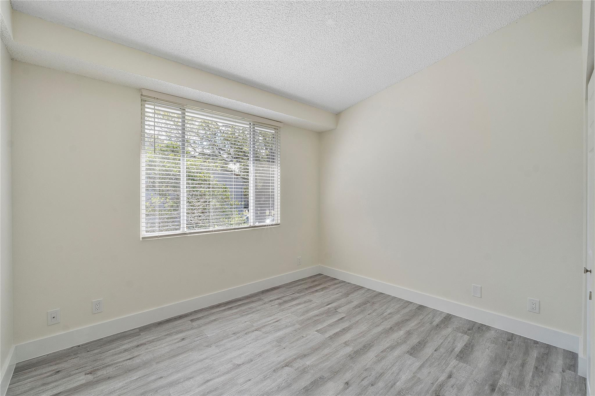 931 Lyons Road, Unit 4204 Coconut Creek, FL 33063 - Photo 5 of 17 an empty room with wooden floor and windows