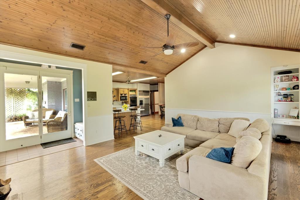 2717 Clear Lake Road Weatherford, TX 76087 - Photo 16 of 40 Living area featuring vaulted wood-paneled ceilings with exposed beams, wood-finish flooring, built-in shelving, and direct access to an enclosed patio through glass doors