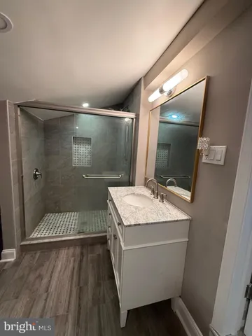 a bathroom with a granite countertop sink a toilet a mirror and shower