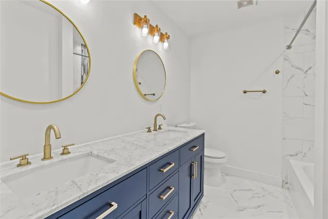 a bathroom with a granite countertop toilet a sink and a mirror