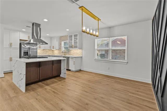 a kitchen with kitchen island granite countertop a sink cabinets and wooden floor