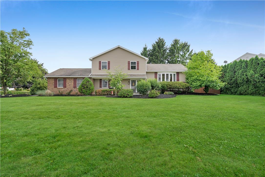 A well-maintained lawn stretches before this charming brick and siding residence, framed by mature trees.