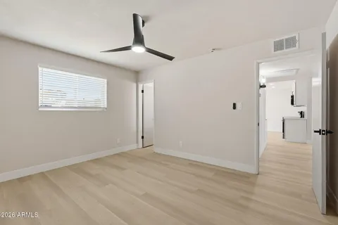 a view of an empty room with wooden floor and a ceiling fan