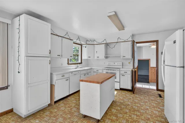 a large white kitchen with a sink window and cabinets