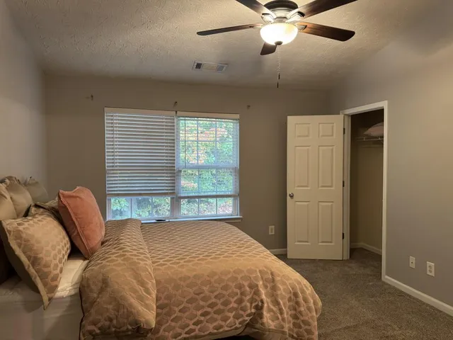 a bed sitting in a bedroom next to a window and a chandelier