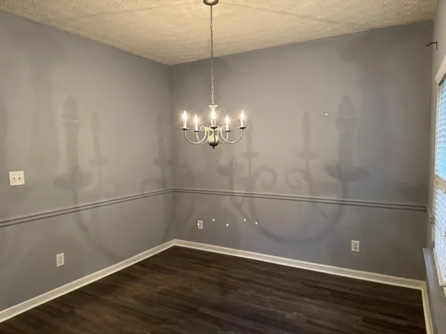 a view of a room with wooden floor and chandelier