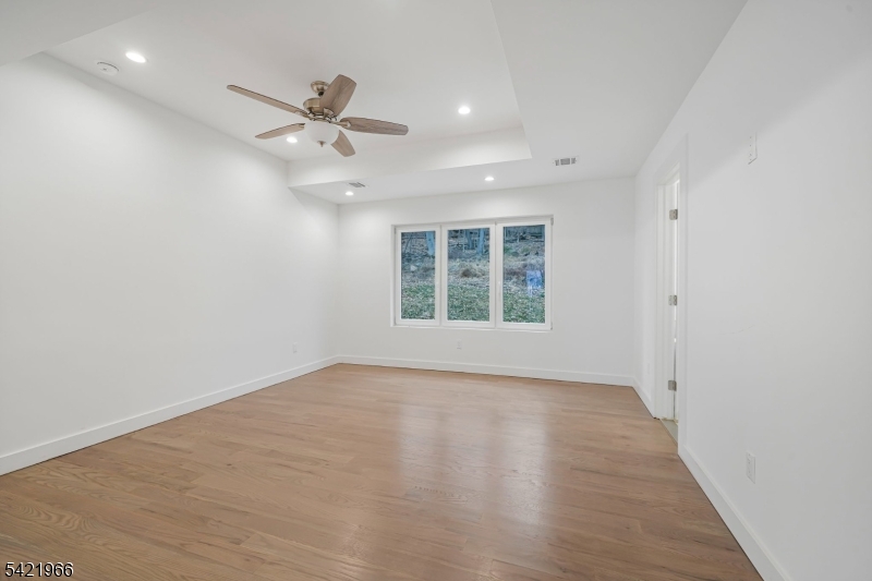 85 Pine Brook Road Montville, NJ 07082 - Photo 30 of 50 an empty room with wooden floor ceiling fan and windows