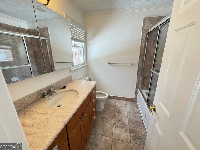 a bathroom with a granite countertop sink toilet and shower