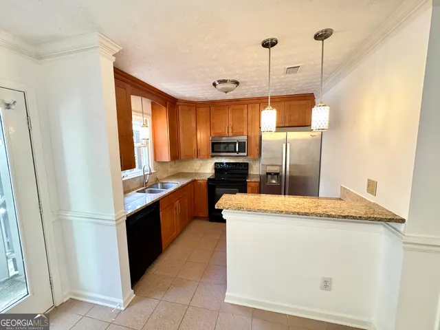 a kitchen with stainless steel appliances granite countertop a refrigerator a stove a sink and dishwasher
