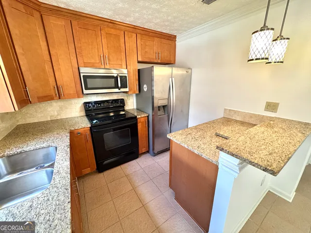 a kitchen with stainless steel appliances granite countertop a refrigerator a stove and a sink