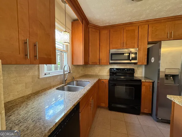 a kitchen with stainless steel appliances granite countertop a sink stove and refrigerator