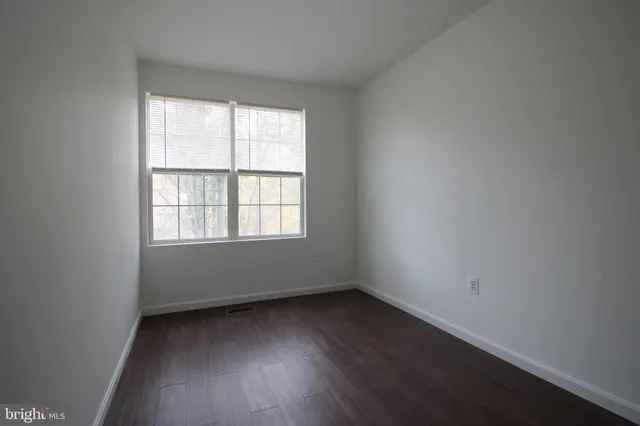 an empty room with wooden floor and mirror