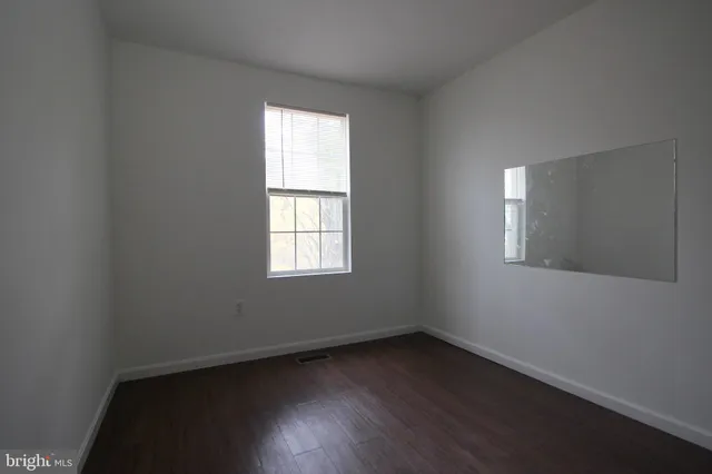 an empty room with wooden floor & closet area