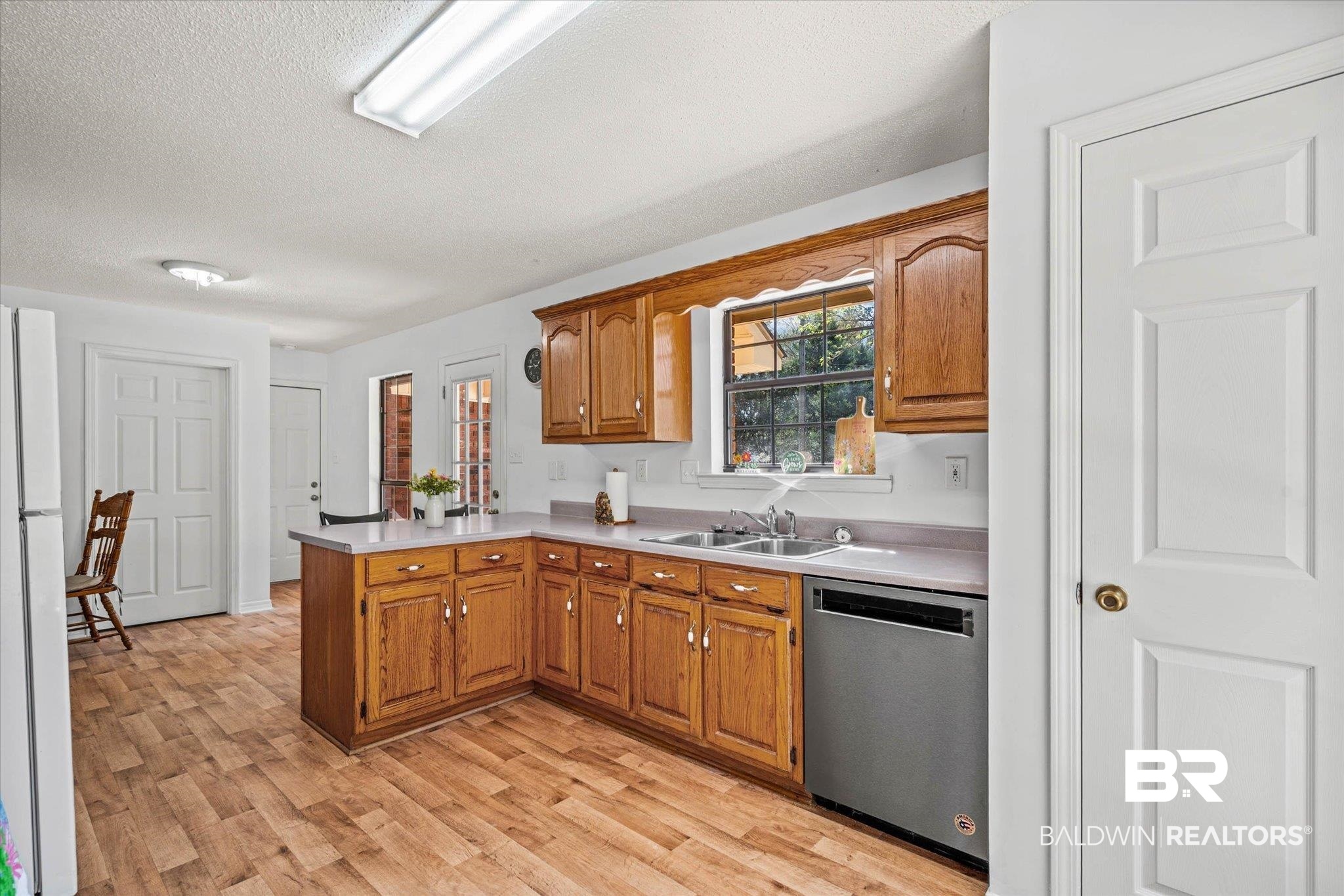 9770 Lakeview Road Bay Minette, AL 36507 - Photo 12 of 44 Kitchen with a peninsula, light countertops, stainless steel dishwasher, wood finish cabinets, and a textured ceiling