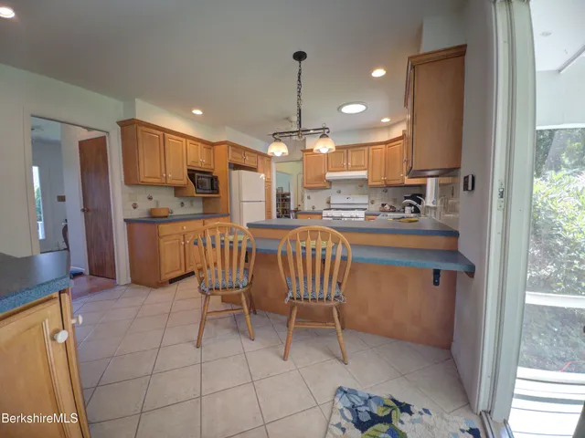a kitchen with stainless steel appliances a sink a stove a refrigerator cabinets and a dining table