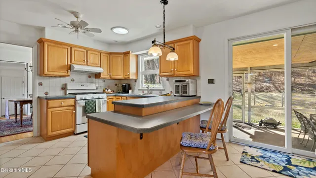 a kitchen with stainless steel appliances granite countertop a stove top oven a sink dishwasher and a dining table with cabinets