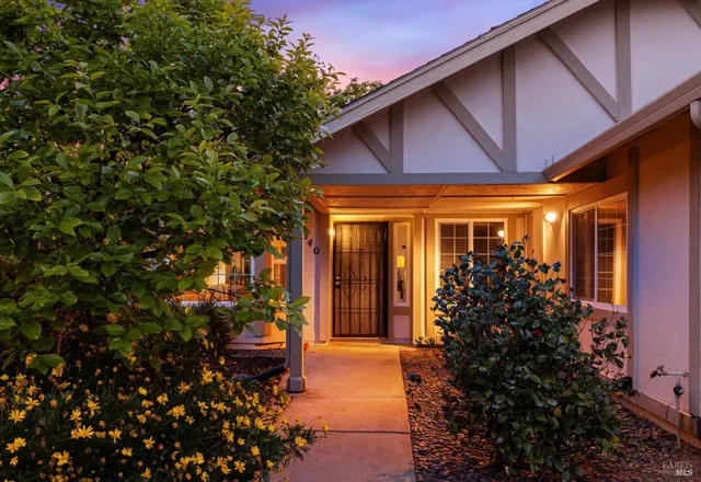 a yellow house with flower garden in front of it
