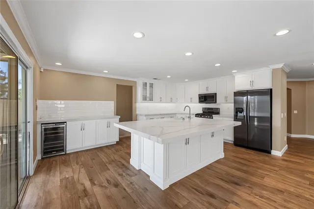 a large kitchen with stainless steel appliances a refrigerator a stove top oven and a center island with wooden floor