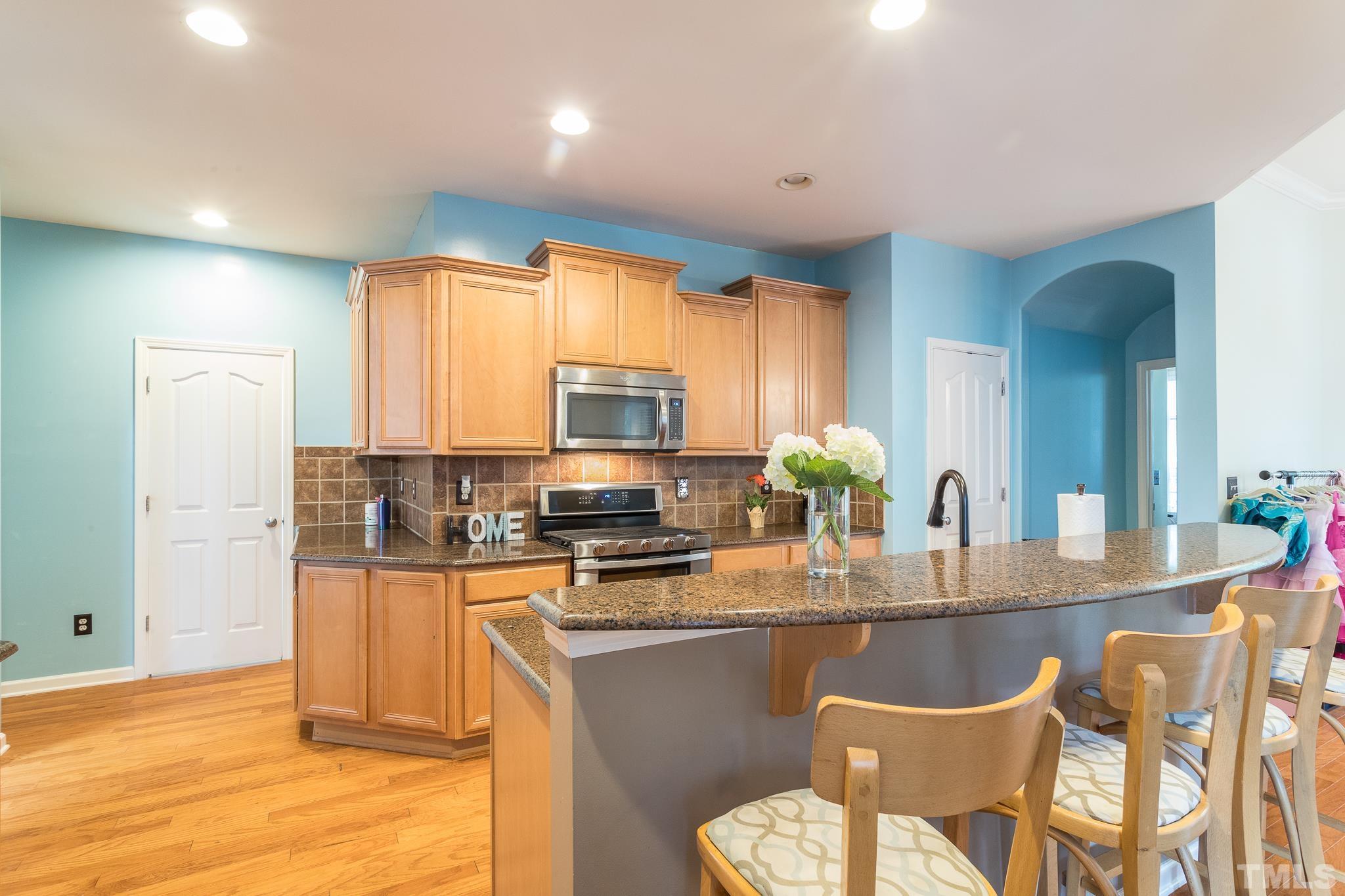 6221 Oconner Street Raleigh, NC 27617 - Photo 8 of 26 a kitchen with stainless steel appliances granite countertop a stove a sink a refrigerator white cabinets and wooden floor