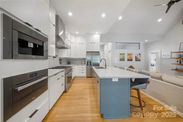 a large kitchen with stainless steel appliances kitchen island granite countertop a large stove top oven a sink dishwasher and white cabinets