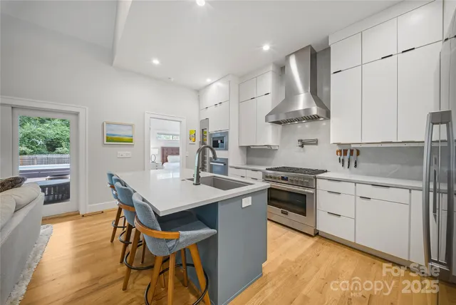 a kitchen with stainless steel appliances granite countertop wooden cabinets a stove a sink a dining table and chairs