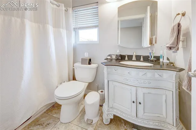 a bathroom with a granite countertop toilet sink and mirror