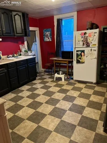 a living room with a black white checkered floor with a gaming machine and red appliances