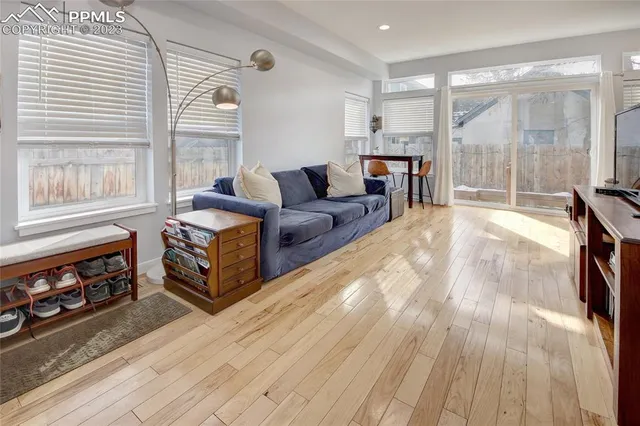 a living room with furniture a large window and wooden floor