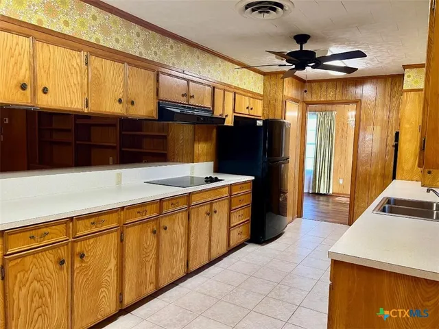 a kitchen with stainless steel appliances granite countertop a refrigerator a sink dishwasher a stove and a dining table with wooden floor