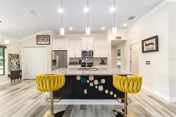 a kitchen with granite countertop kitchen island stainless steel appliances a refrigerator a stove a sink a dining table and chairs