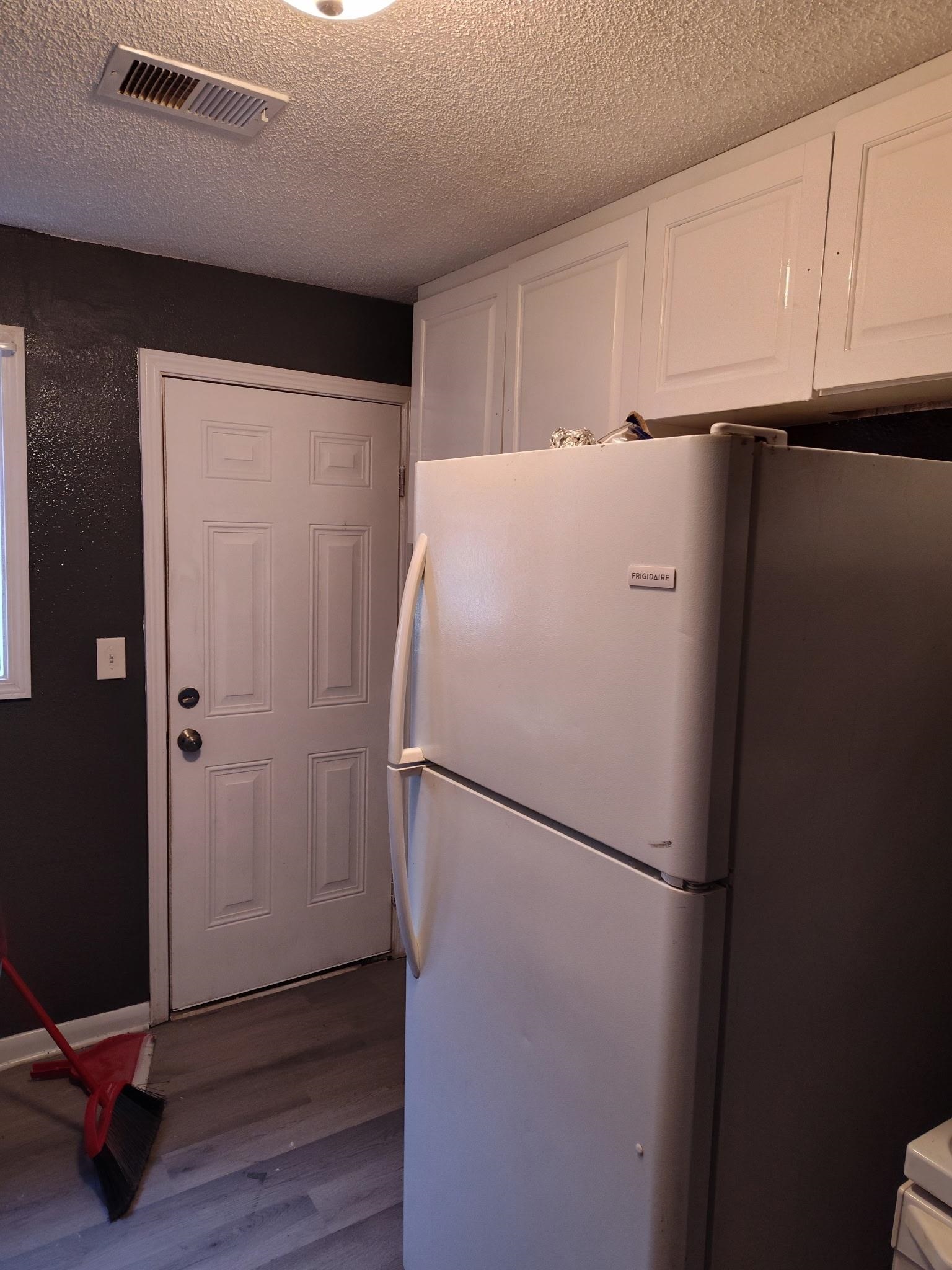 258 Silverage Avenue Memphis, TN 38109 - Photo 4 of 8 Kitchen featuring white cabinets, freestanding refrigerator, a textured ceiling, and dark wood-style flooring